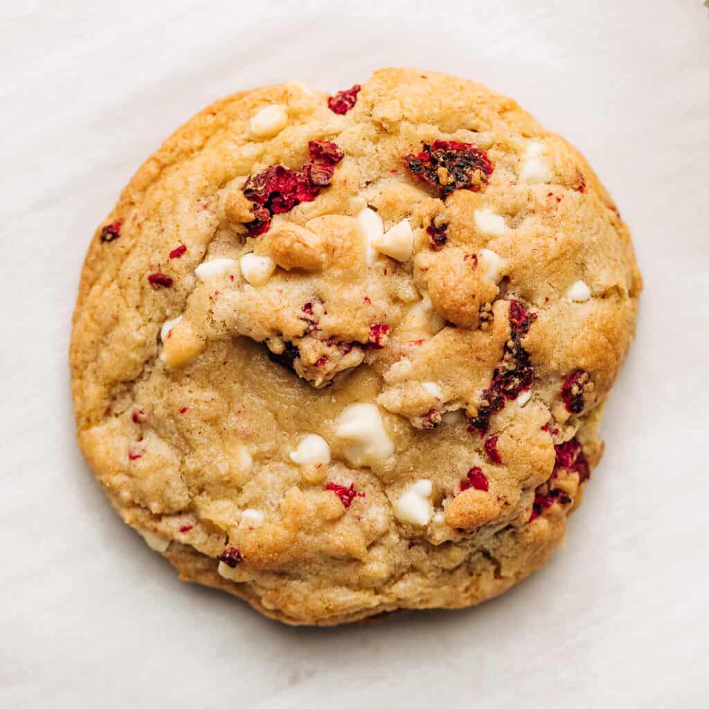Raspberry white chocolate chip cookie on parchment paper.