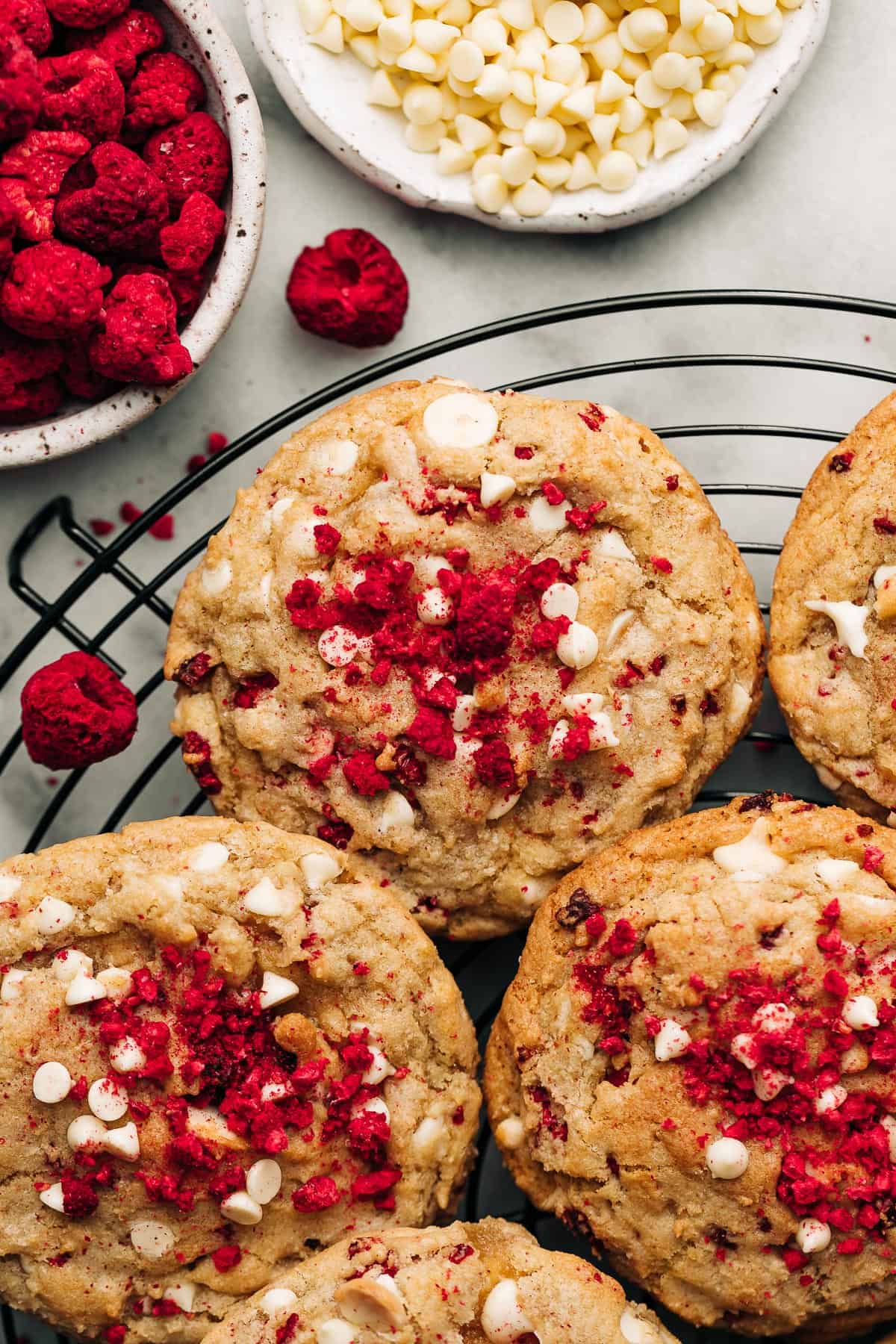 Raspberry white chocolate chip cookies on a black wire rack.