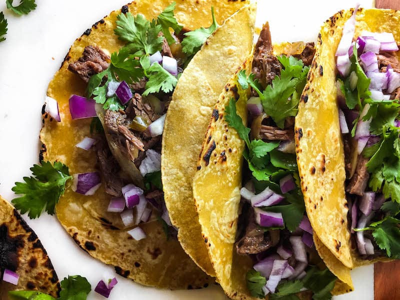 Delicious, tender, fall-apart meat stuffed in corn tortillas and topped with avocado, cilantro, and onion - these Easy Shredded Beef Tacos are so simple and tasty!