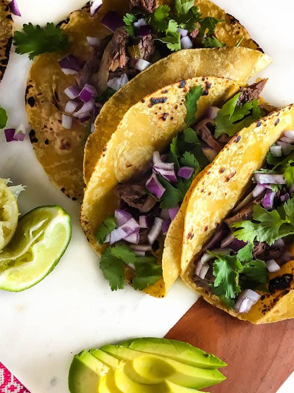 Delicious, tender, fall-apart meat stuffed in corn tortillas and topped with avocado, cilantro, and onion - these Shredded Beef Tacos (Crock Pot) are so simple and tasty!