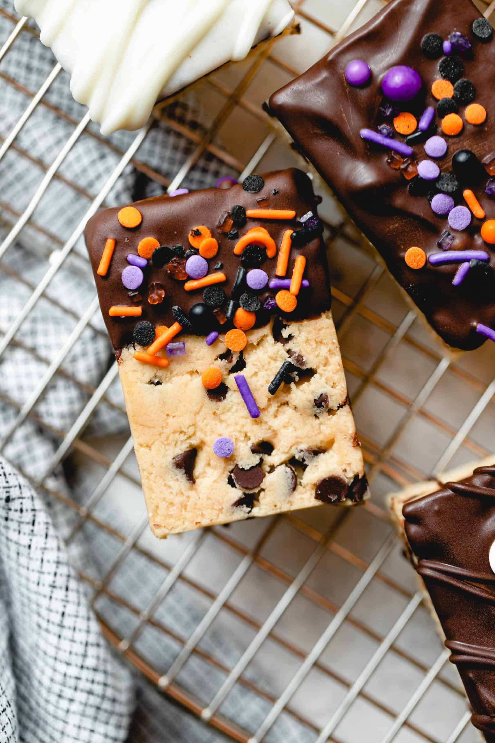 Chocolate dipped cookie dough rice krispie treat with Halloween sprinkles on a wire rack