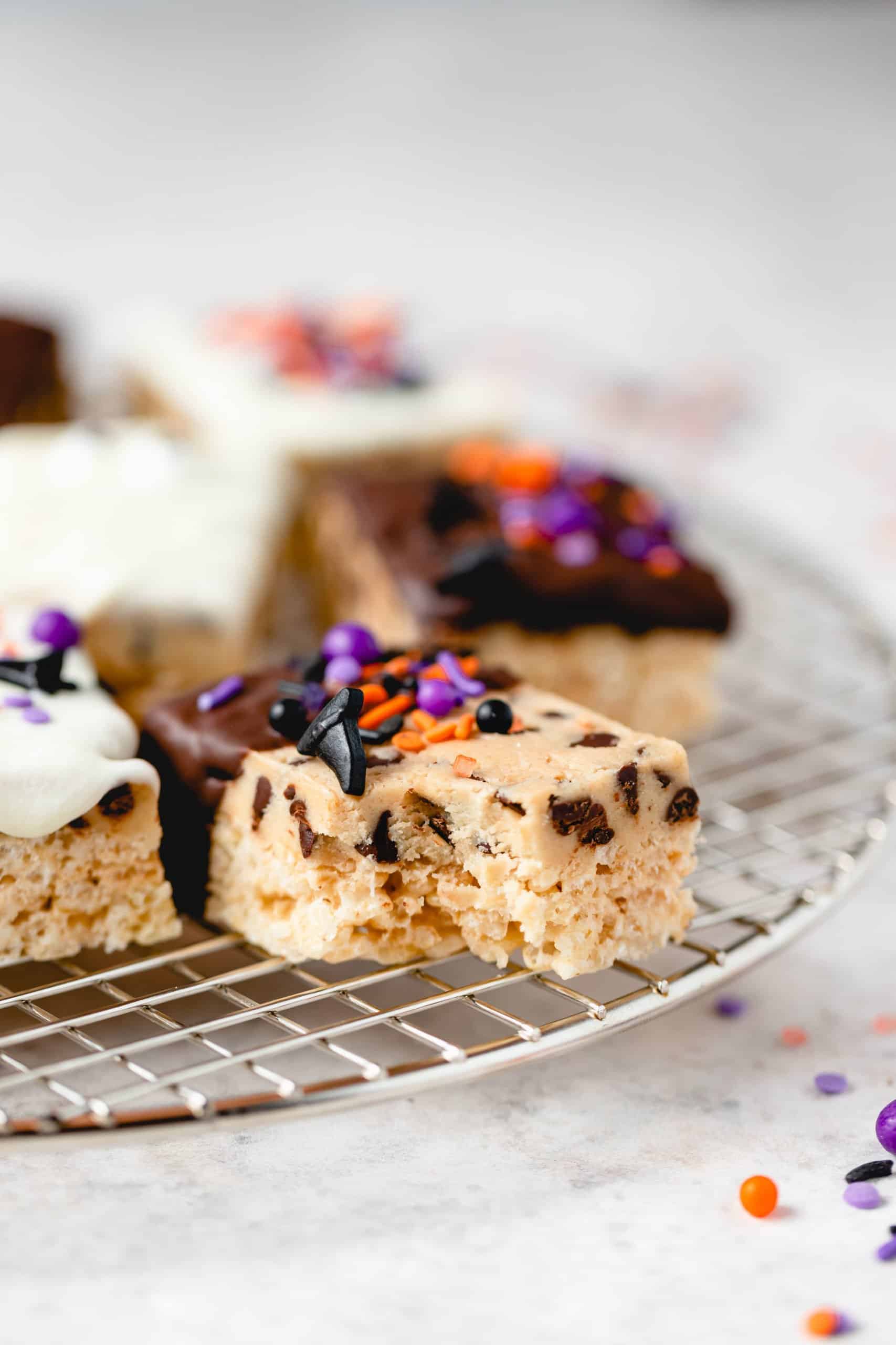 bite shot of a halloween themed cookie dough rice krispie treat on a wire rack