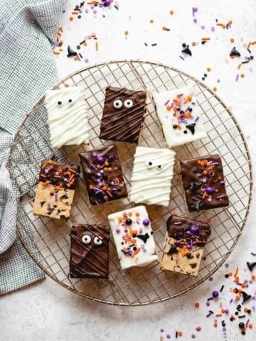 Halloween decorated cookie dough rice krispie treats on a round wire rack