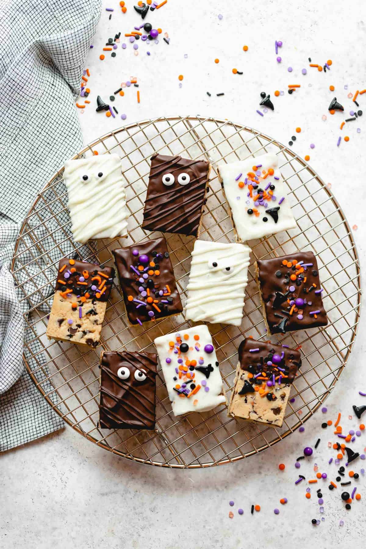 Halloween decorated cookie dough rice krispie treats on a round wire rack