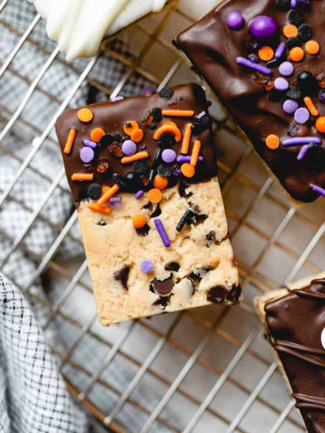 Chocolate dipped cookie dough rice krispie treat with Halloween sprinkles on a wire rack