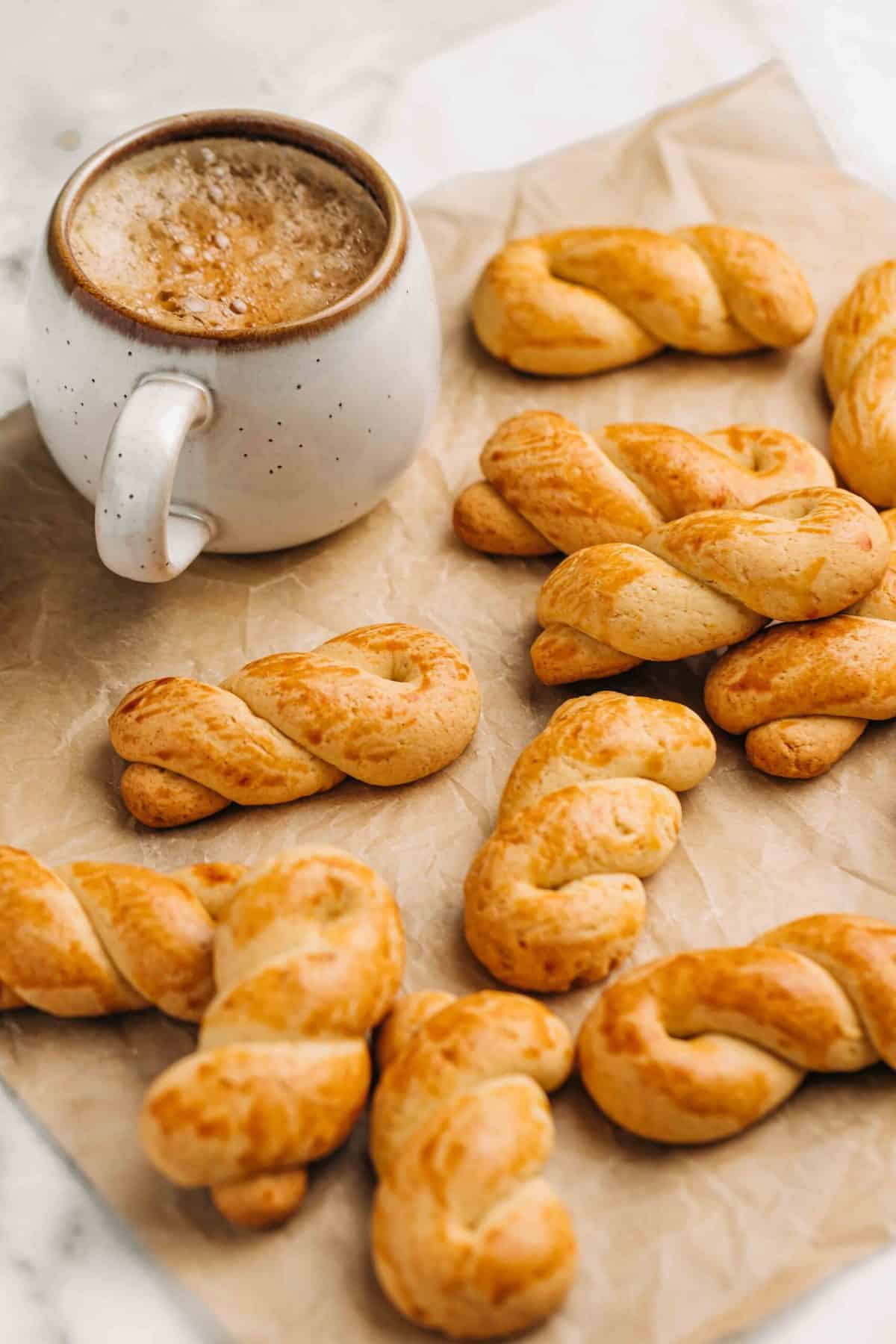 Koulorakia and a cup of coffee on brown parchment paper.