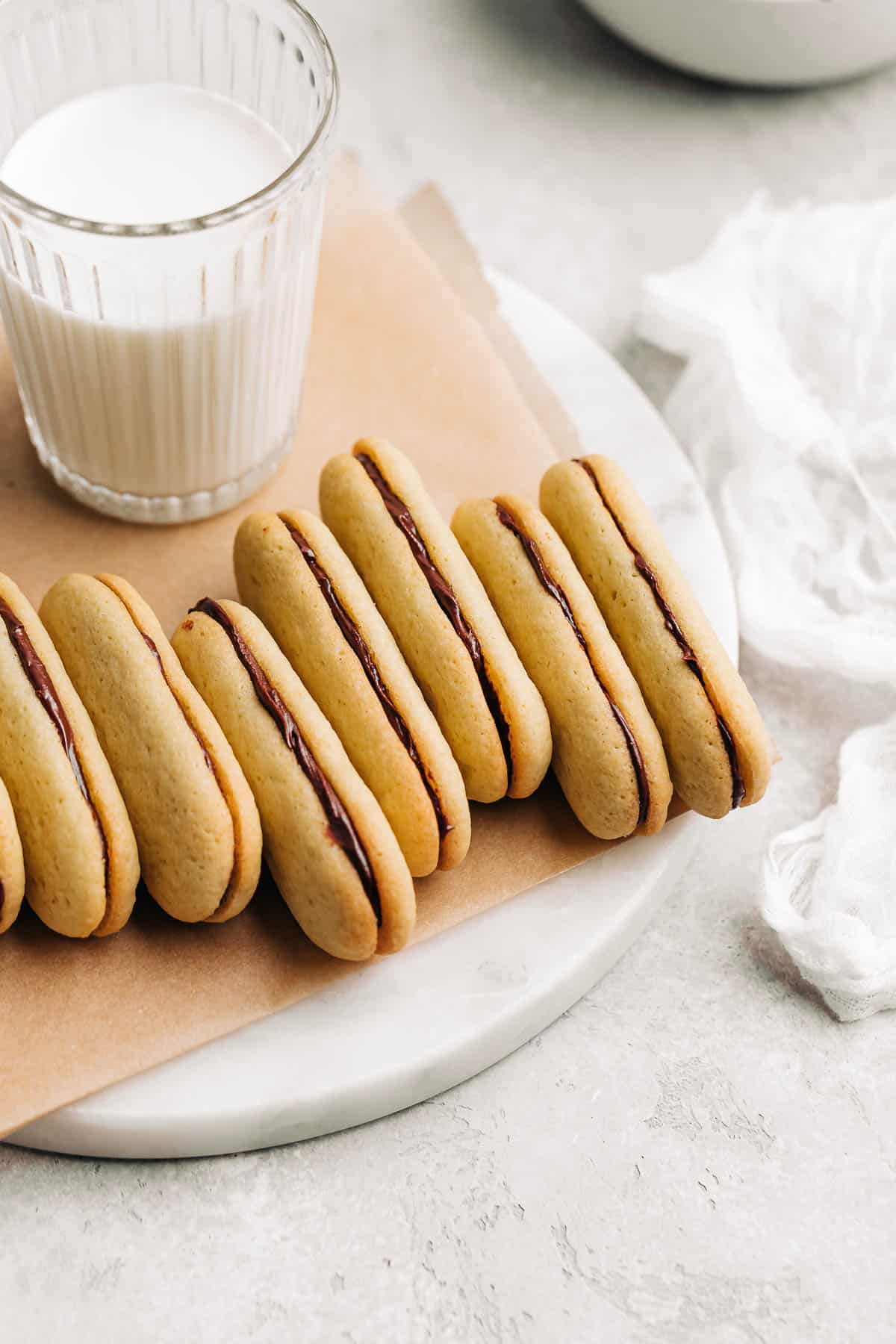 Milano cookies and a glass of milk on brown parchment paper.