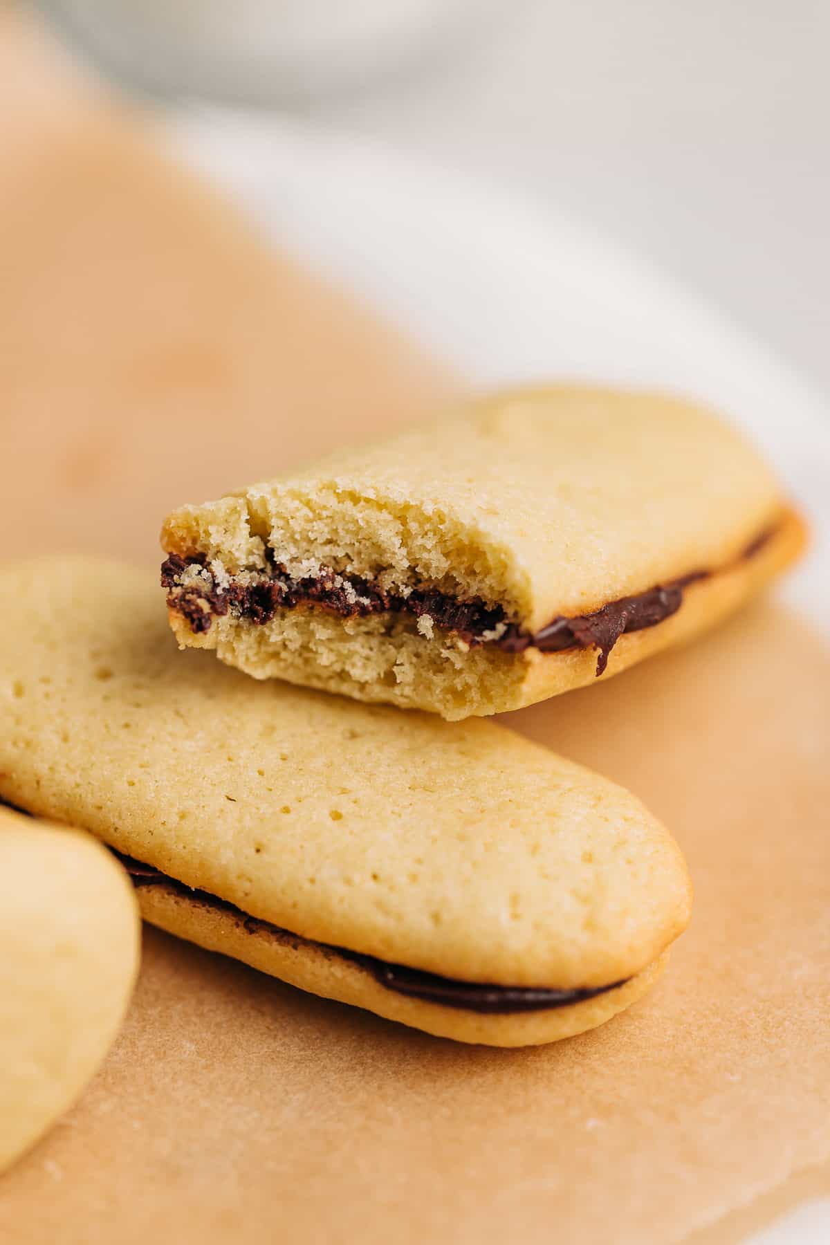 Bite shot of a Milano cookie on brown parchment paper.