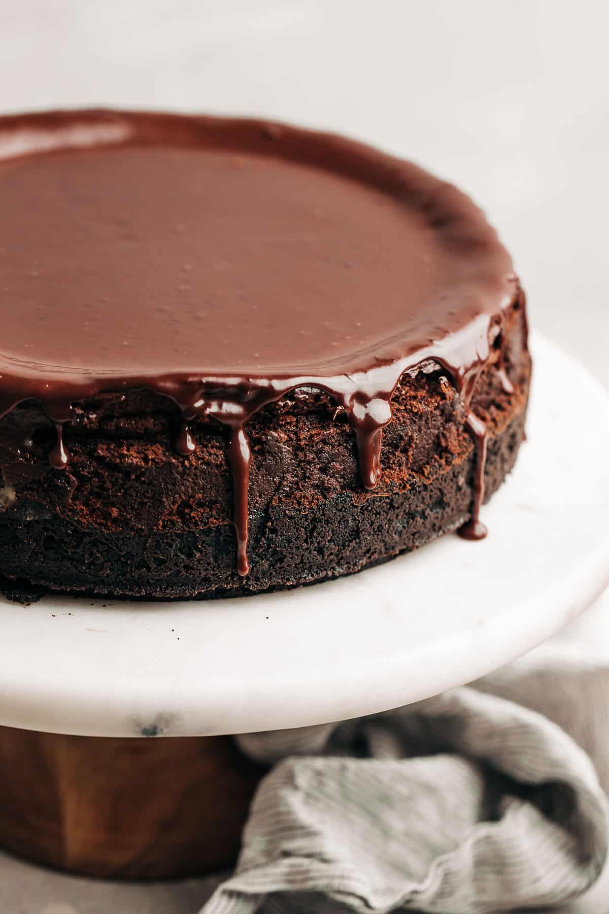 chocolate cheesecake with chocolate ganache on a marble cake stand.