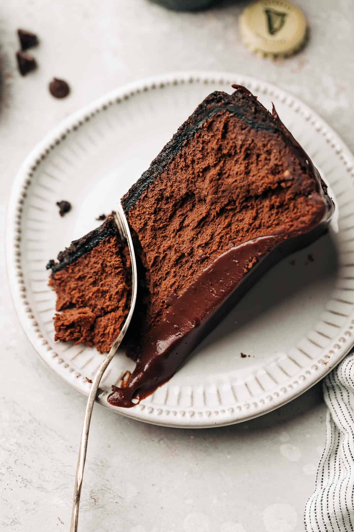 slice of chocolate cheesecake with ganache on a plate.
