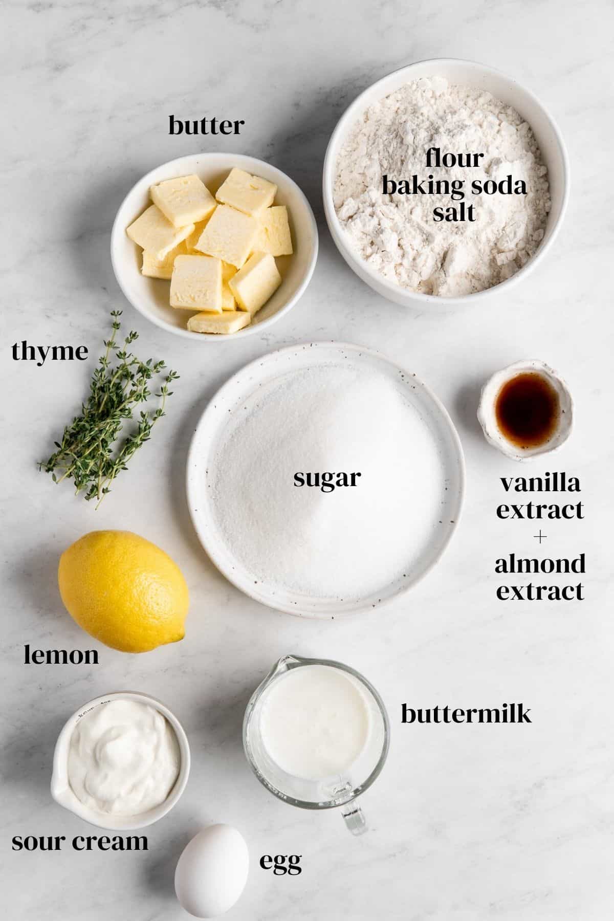 butter, flour, baking soda, salt, vanilla extract, almond extract, buttermilk, sour cream, lemon, sugar, thyme in small bowls.