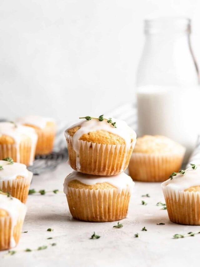 Two lemon thyme muffins with glaze stacked on top of each other.