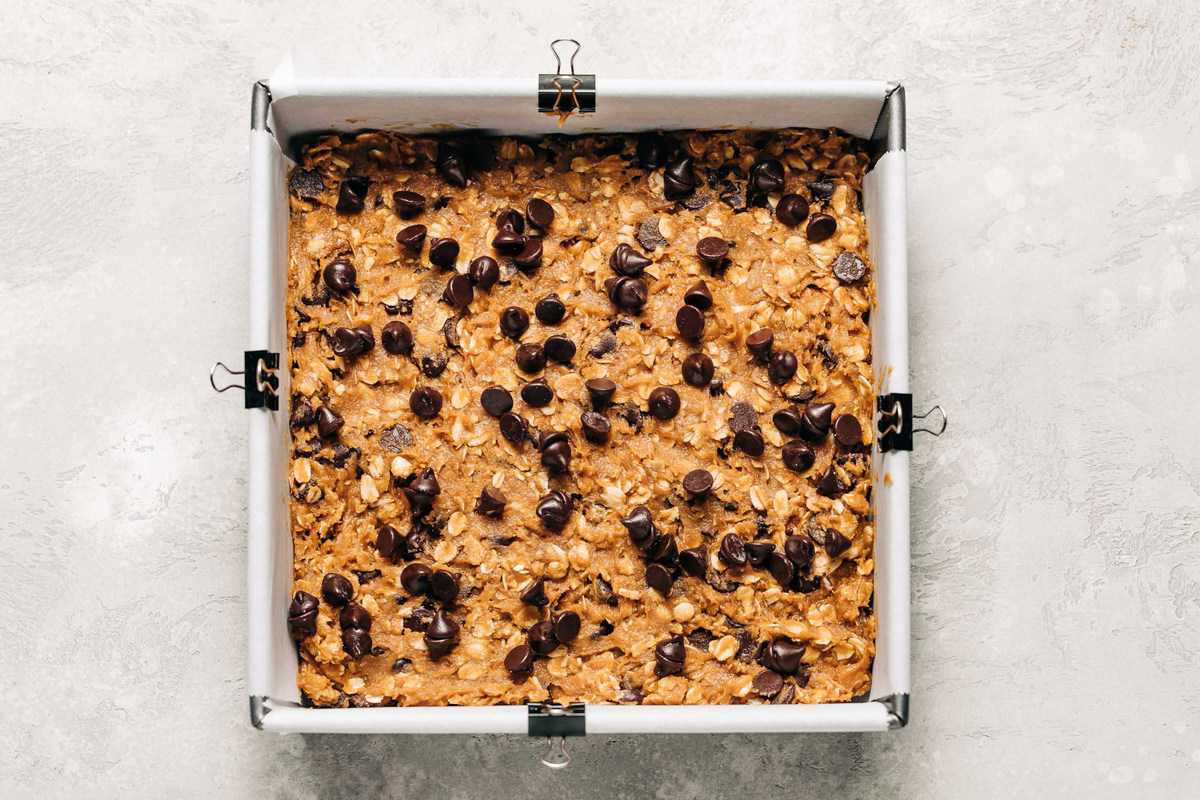 Unbaked oatmeal chocolate chip cookie bars in a baking pan.