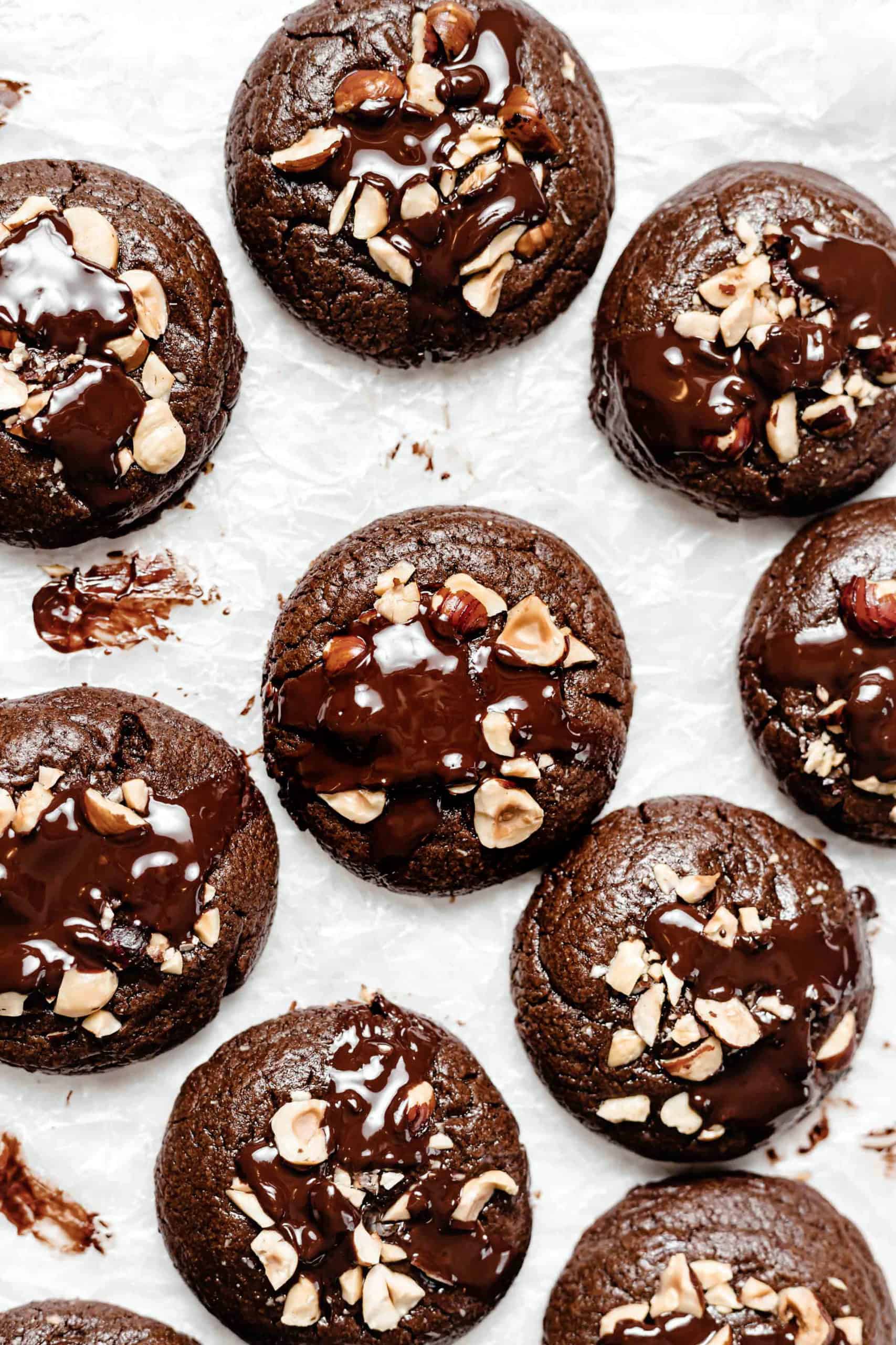 fudgy chocolate hazelnut brownie cookies with chocolate puddles on parchment paper