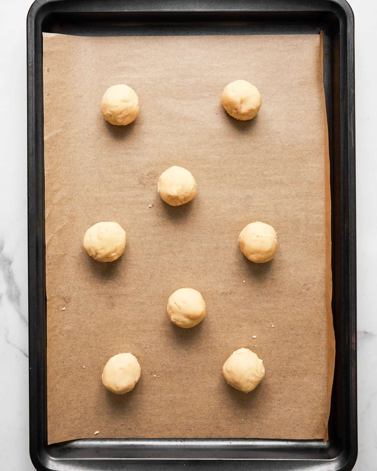 unbaked kourabiedes on a baking sheet.