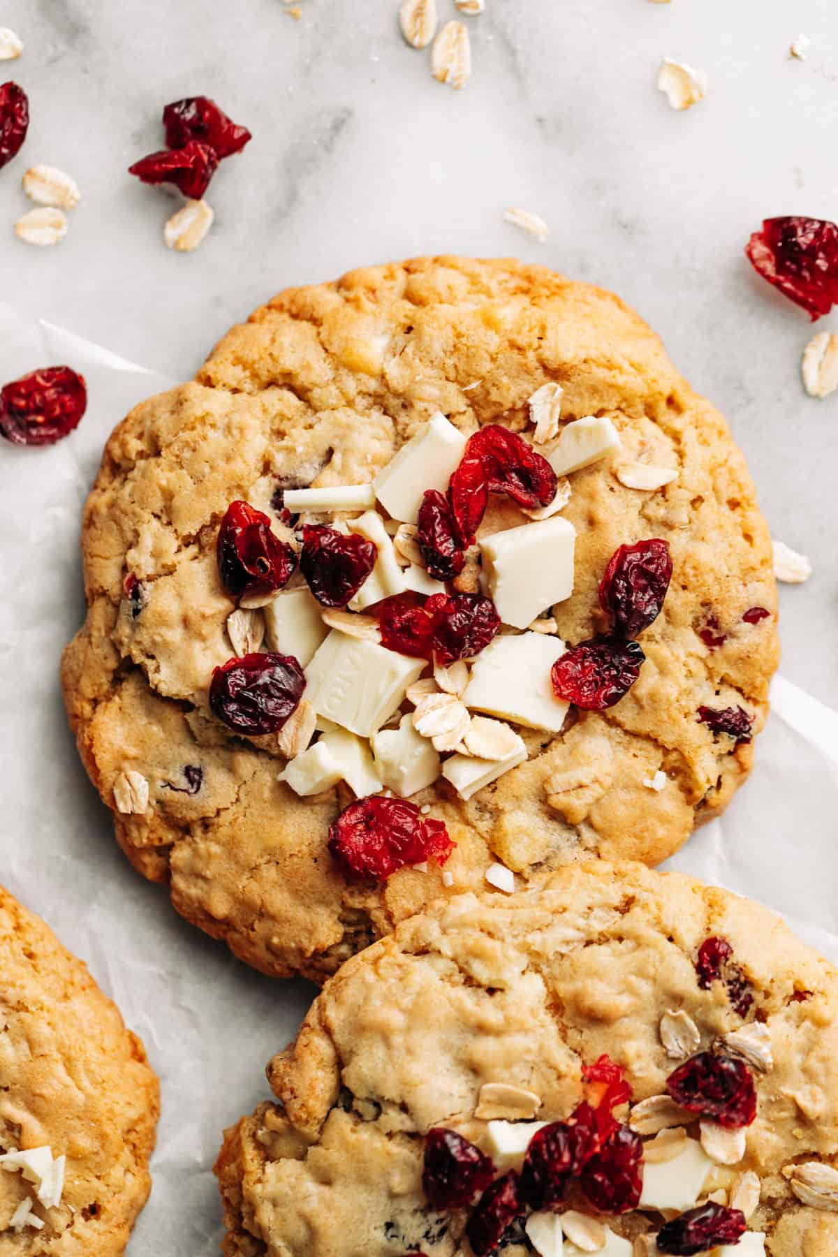 Cranberry and white chocolate oatmeal cookies on parchment paper.