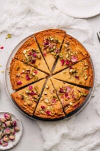 Persian love cake toped with dried rose petals and pistachios cut into 8 slices.