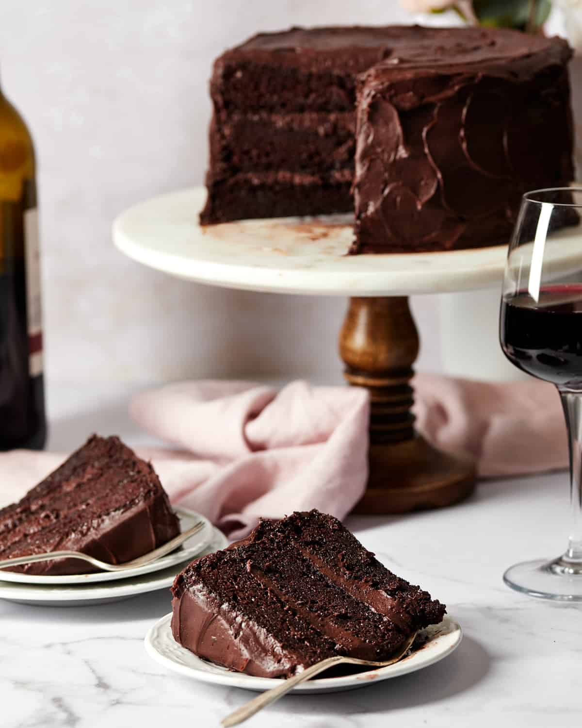two slice of red wine chocolate cake on plates with the cake in the background.