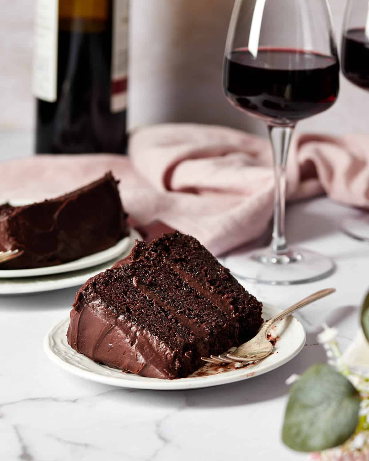 two slices of red wine chocolate cake with a glass and bottle of red wine.
