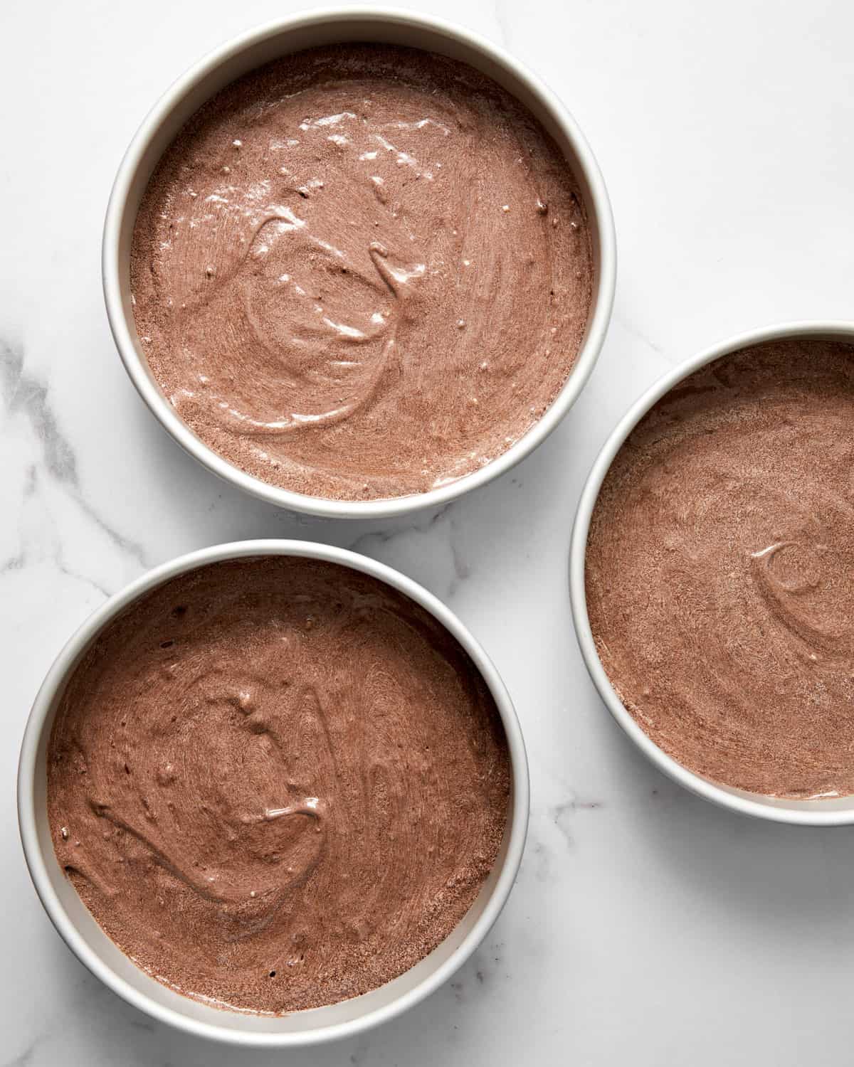 red wine chocolate cake batter in 3 cake pans.