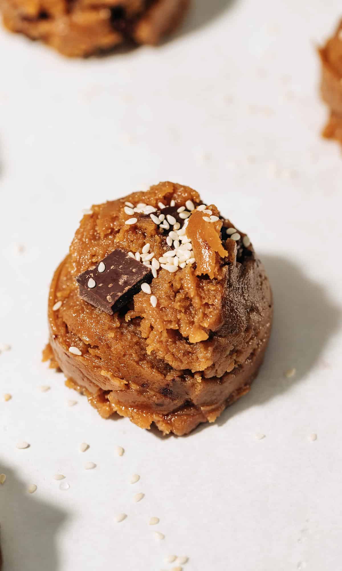 chocolate chip tahini cookie dough ball on parchment paper.
