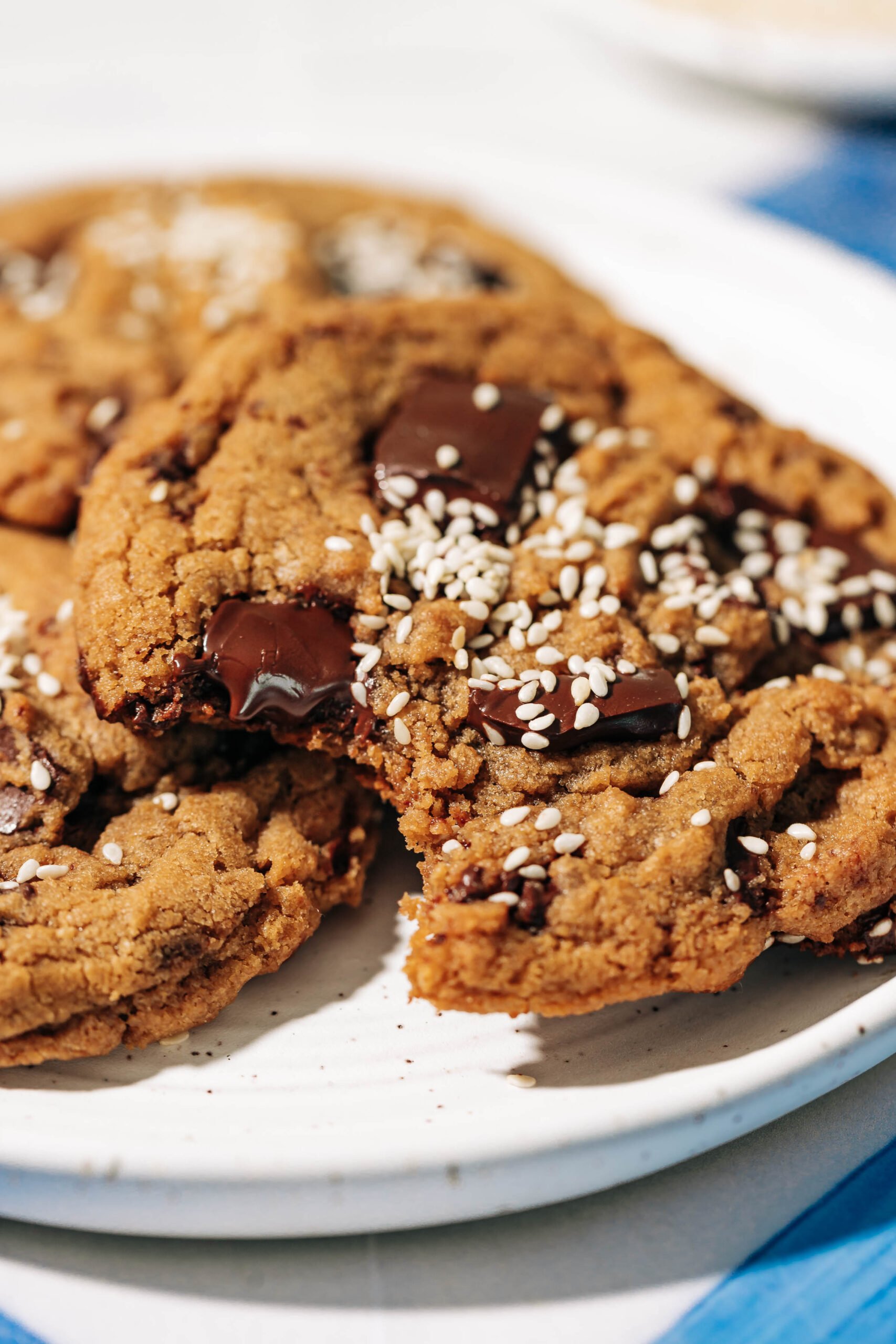 bite shot of tahini chocolate chip cookies on a white ceramic plate.