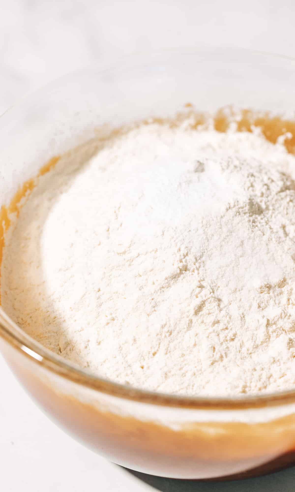 flour, baking soda, and salt on top of wet ingredients in a bowl.