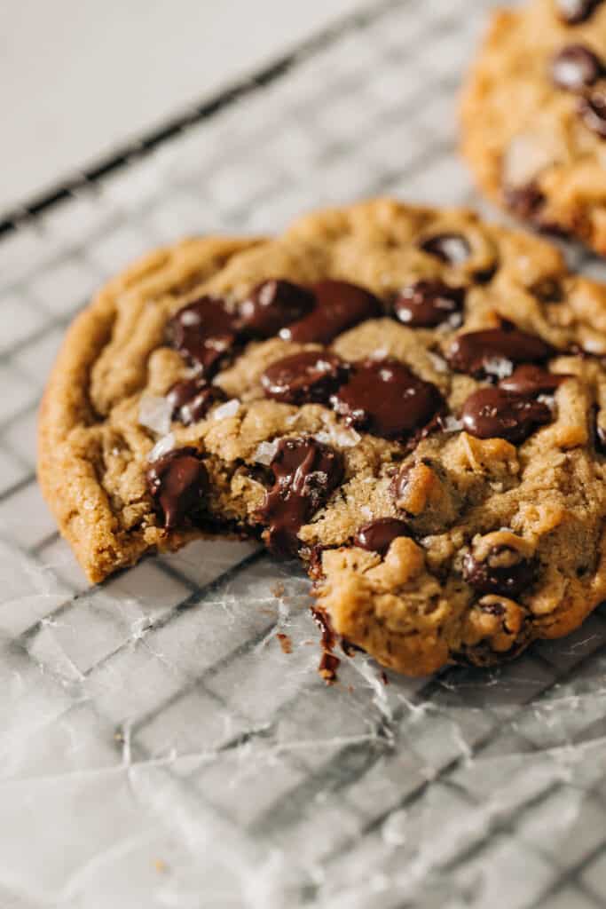 Bite shot of a peanut butter oatmeal chocolate chip cookie on a wire rack with wax paper.