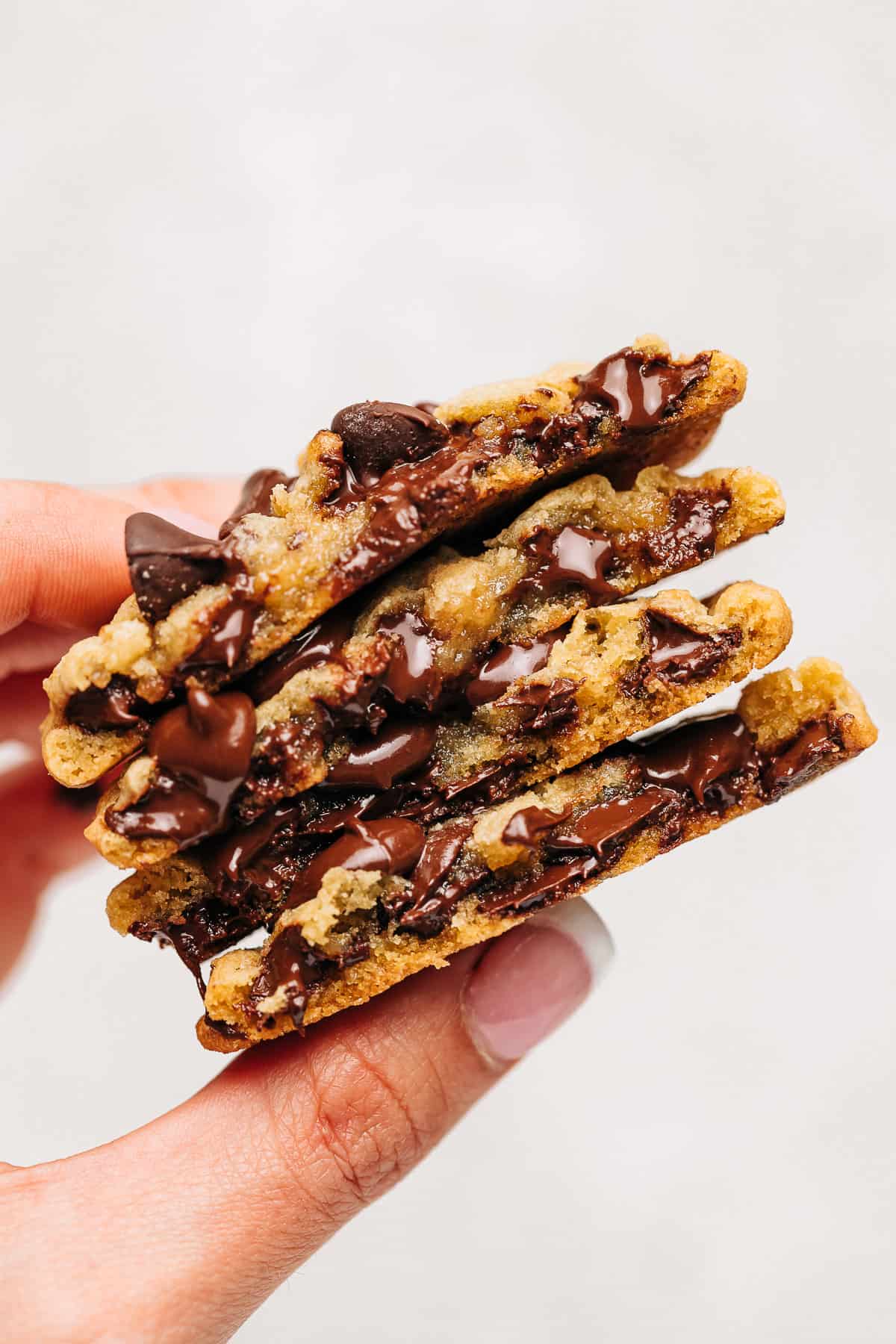 Hand holding stack of chocolate chip cookies.