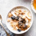 bulgur breakfast bowl topped with coconut flakes, blueberries, cinnamon, and honey