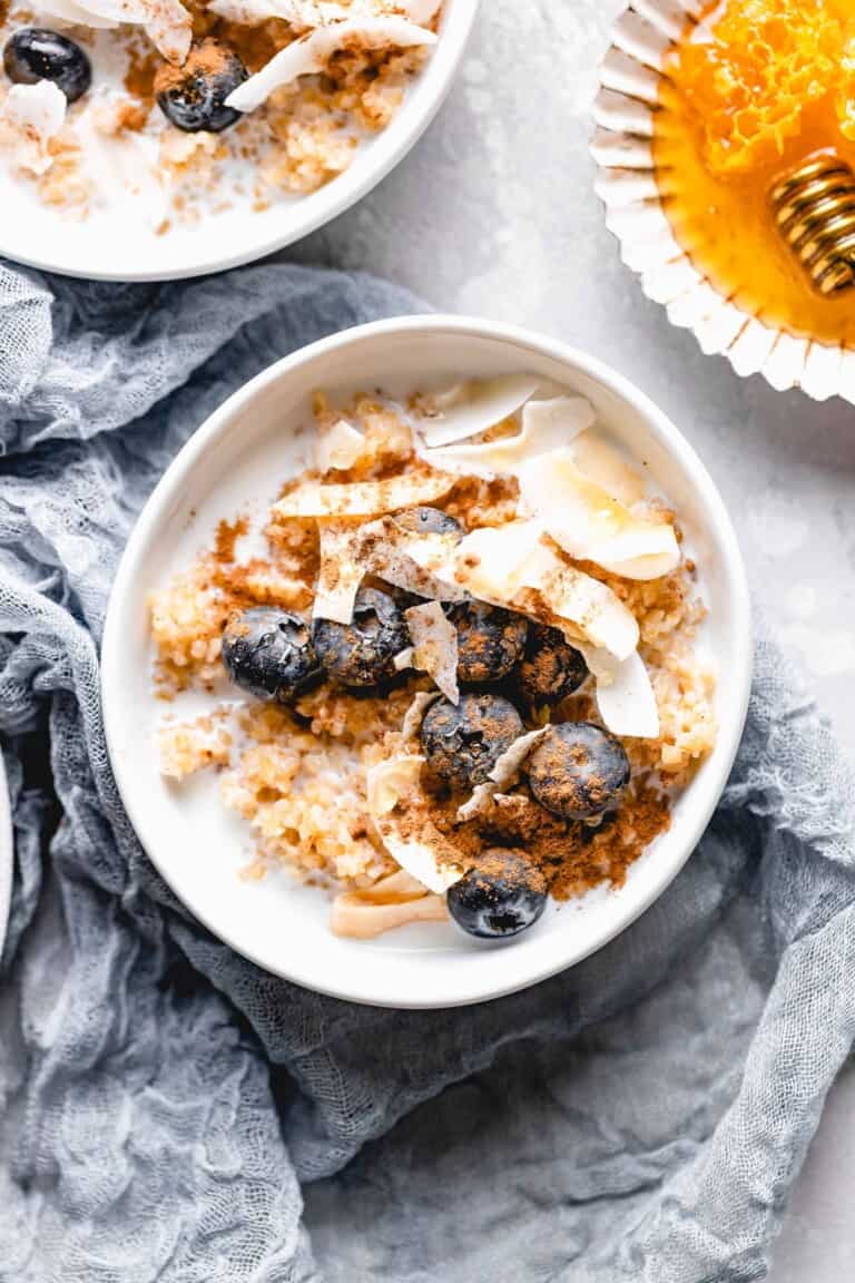 bulgur breakfast bowl topped with coconut flakes, blueberries, cinnamon, and honey