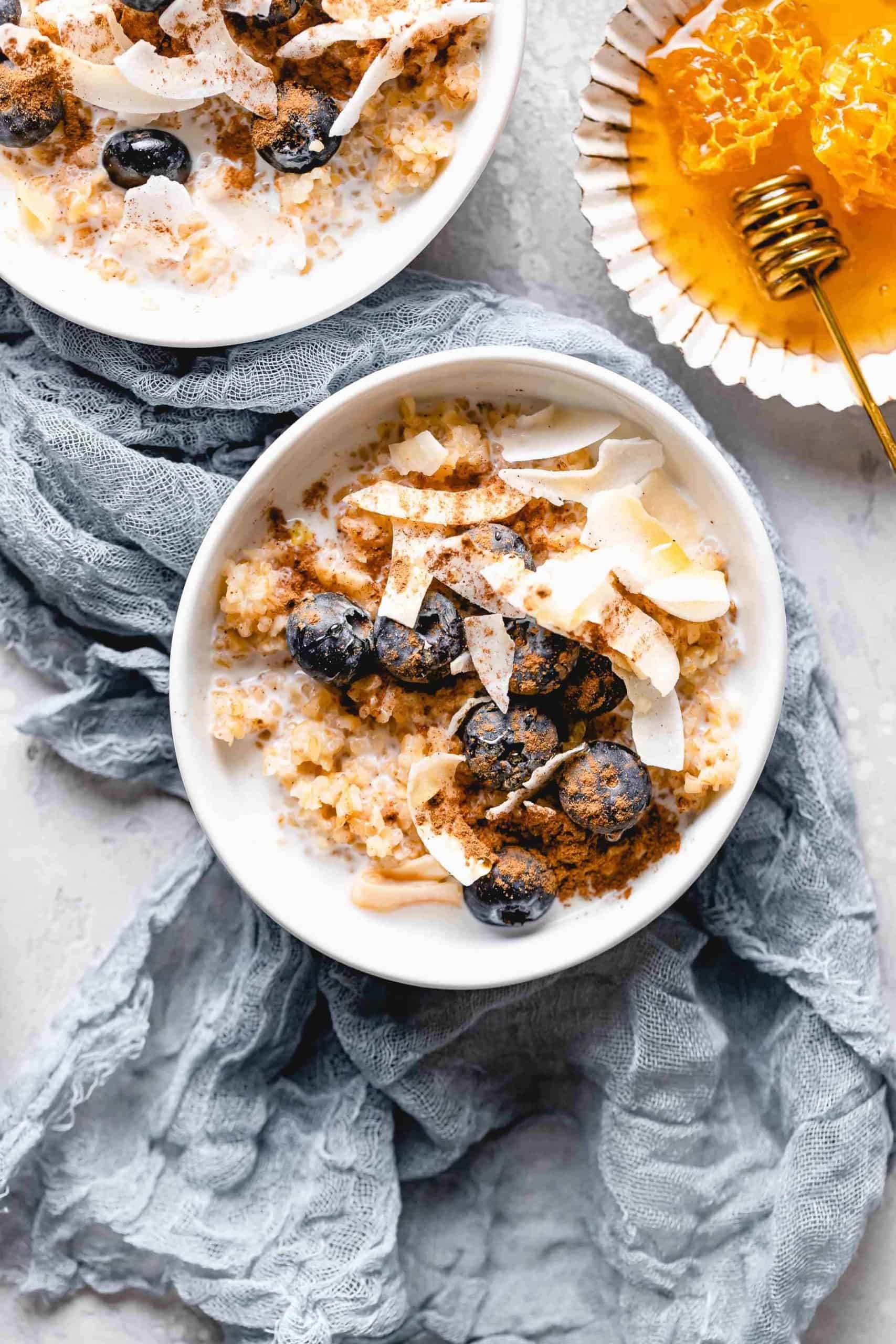 bulgur breakfast bowl topped with coconut flakes, blueberries, cinnamon, and honey