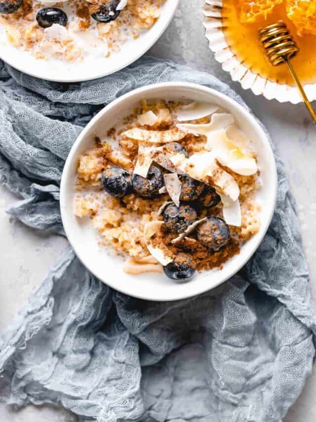 bulgur breakfast bowl topped with coconut flakes, blueberries, cinnamon, and honey