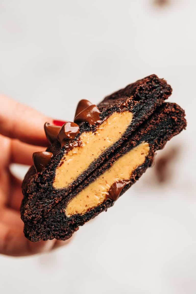 Hand holding a peanut butter stuffed chocolate cookie cut in half