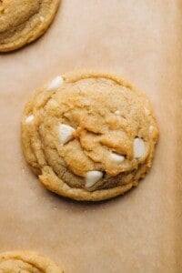 single white chocolate chip cookie on brown parchment paper.