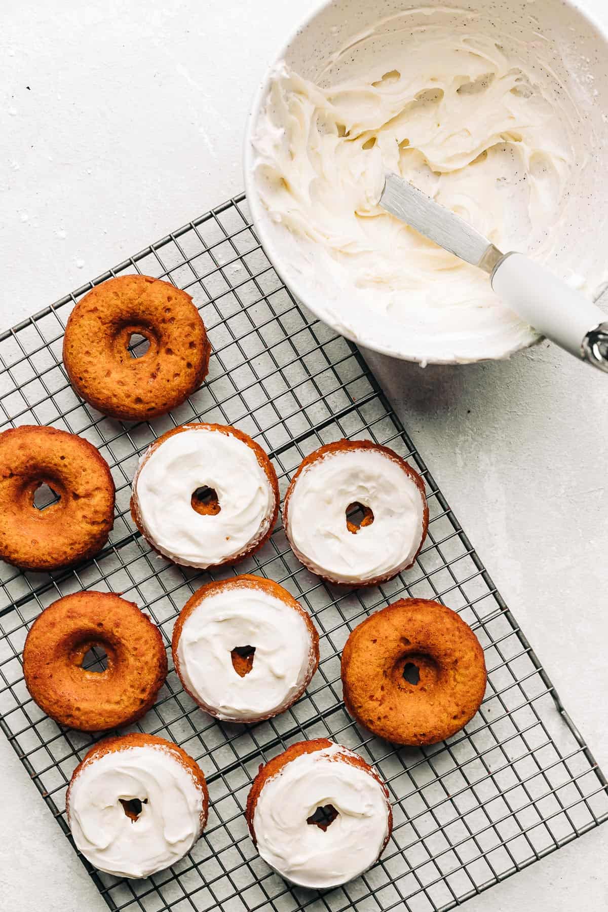 frosted carrot cake donuts on a wire rack.