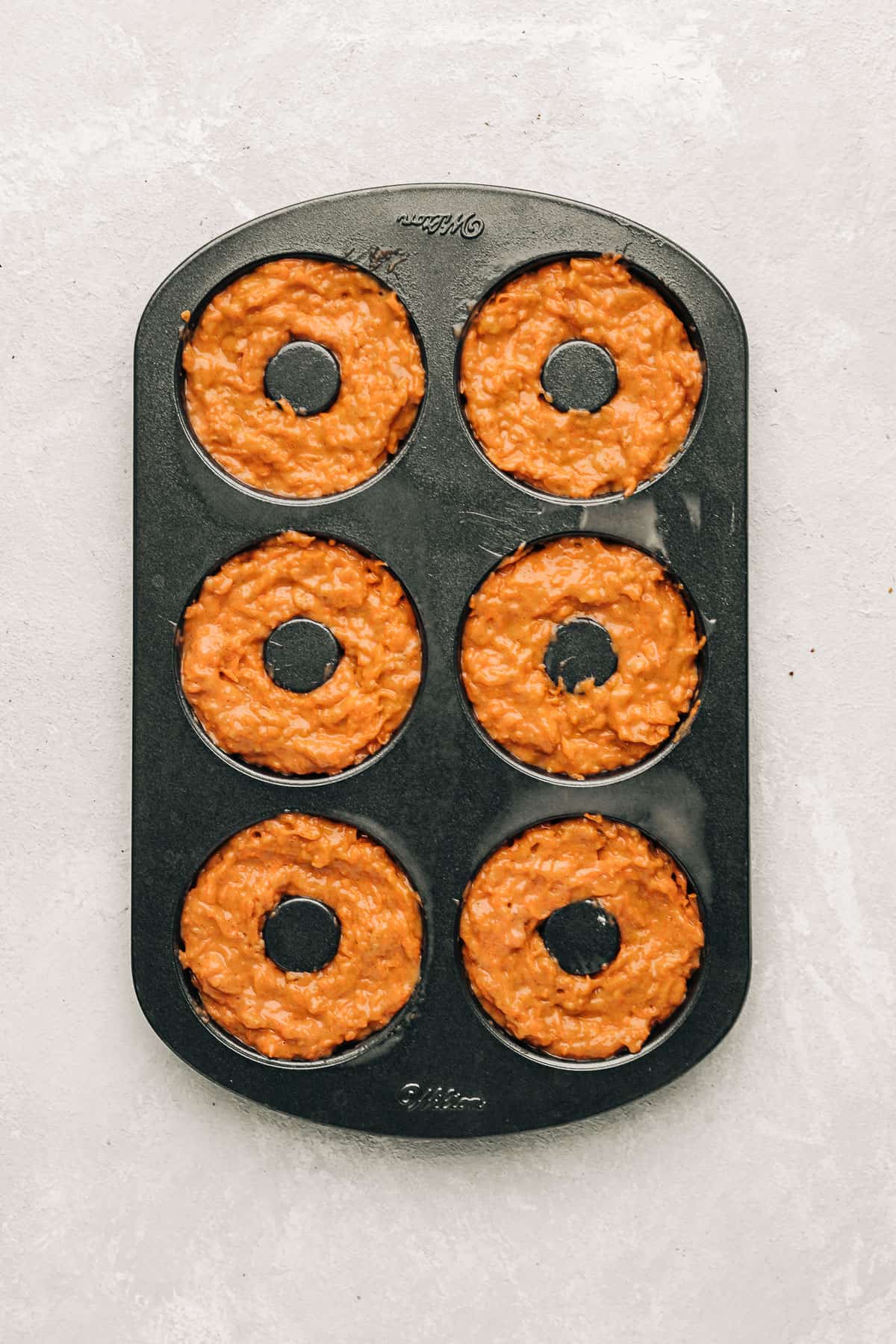 unbaked carrot cake donuts in a donut pan.