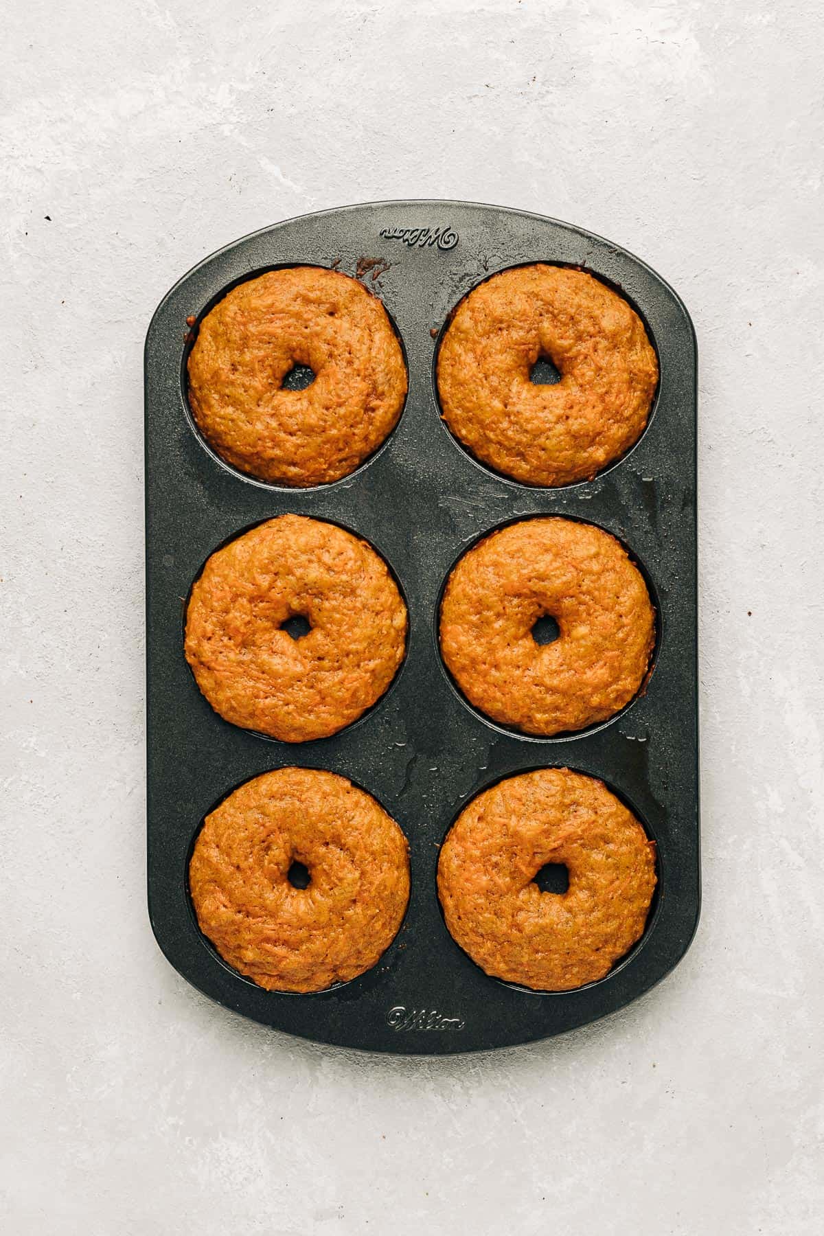 baked carrot cake donuts in a donut pan.