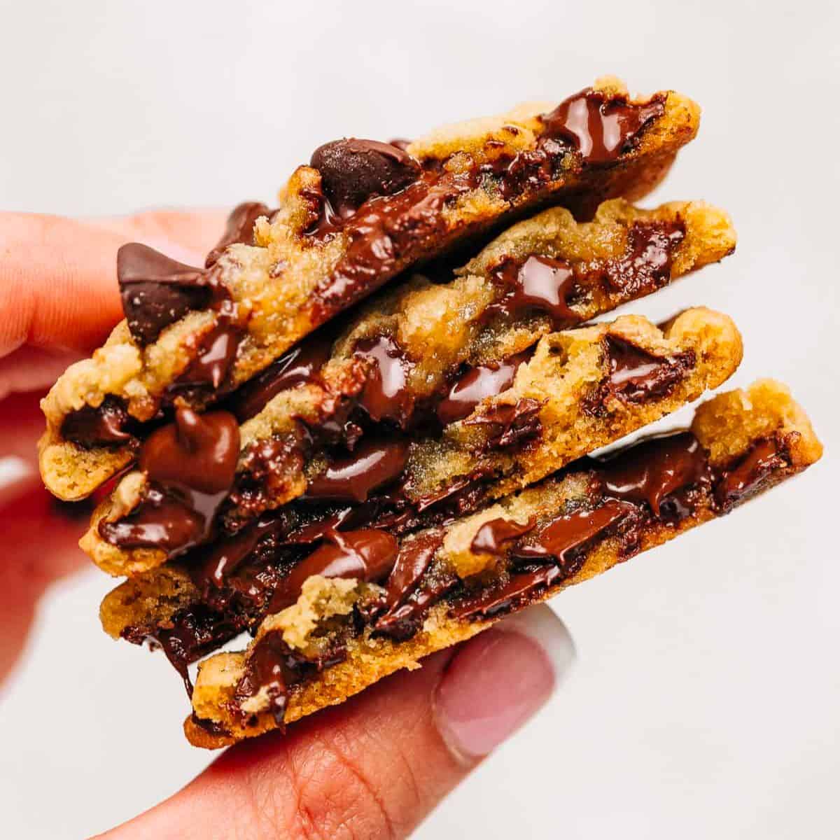 Hand holding stack of chocolate chip cookies.