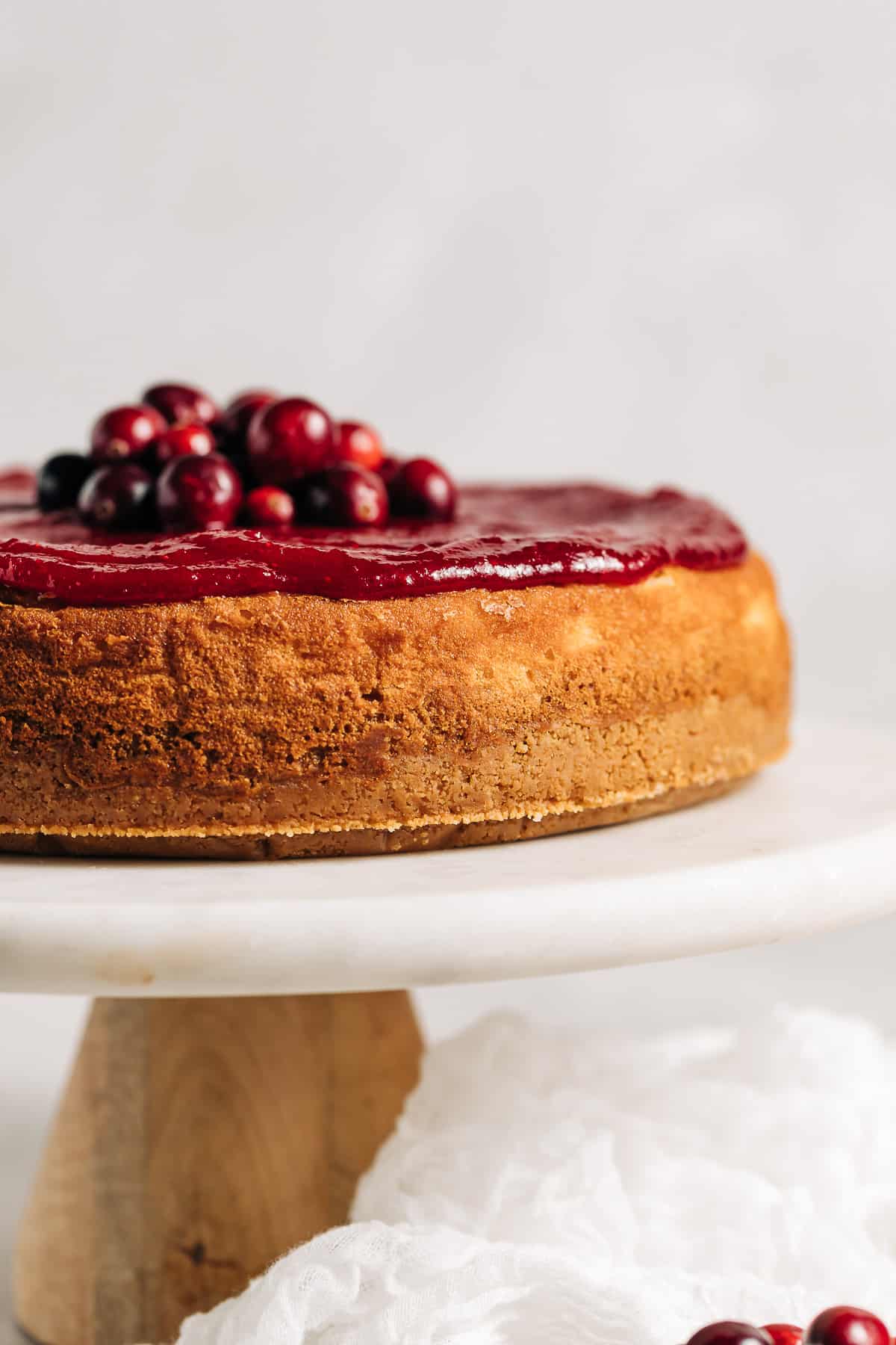white chocolate cheesecake with cranberry topping on a cake stand.