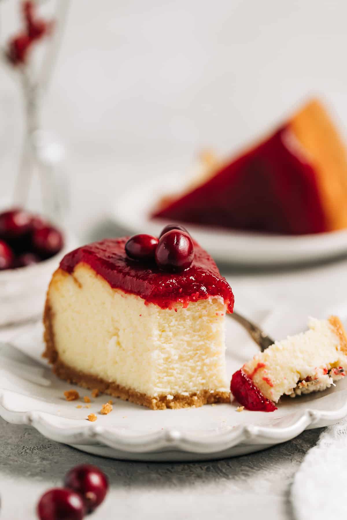 slice of white chocolate cranberry cheesecake on a plate.