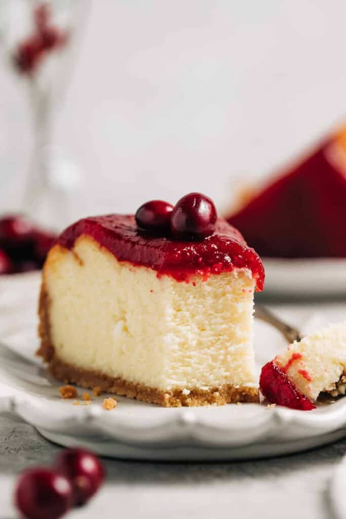 slice of white chocolate cranberry cheesecake on a plate.