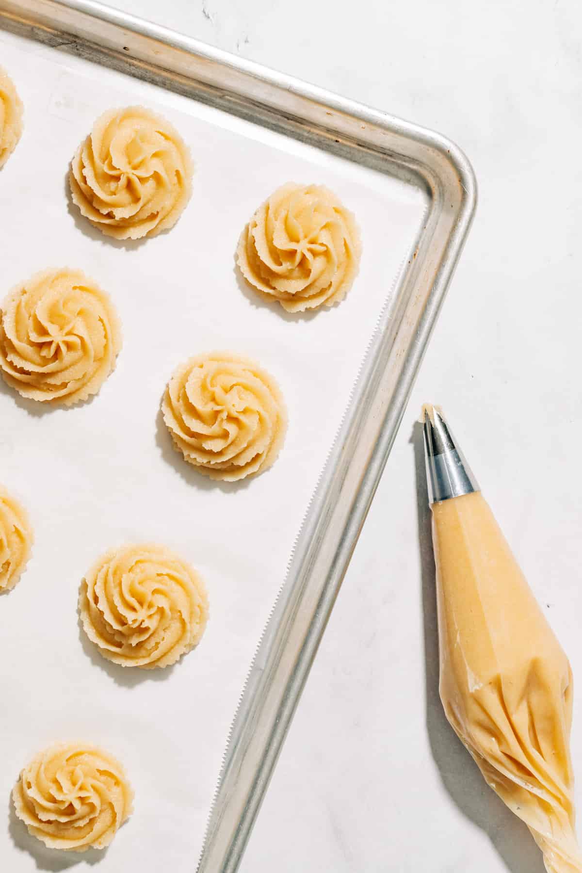 amygdalota on a baking tray with a piping bag.