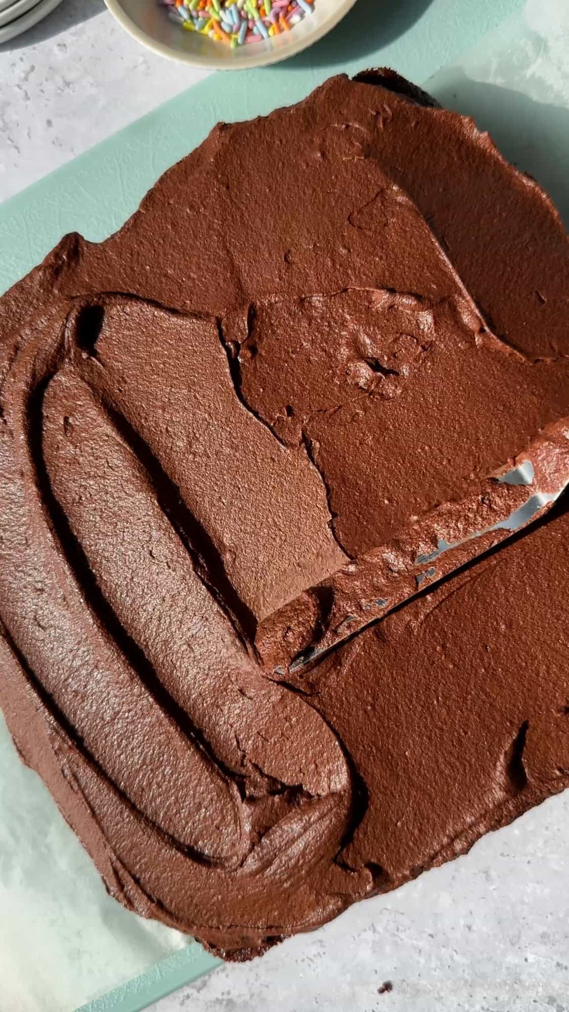 chocolate frosting being spread on a cake. 
