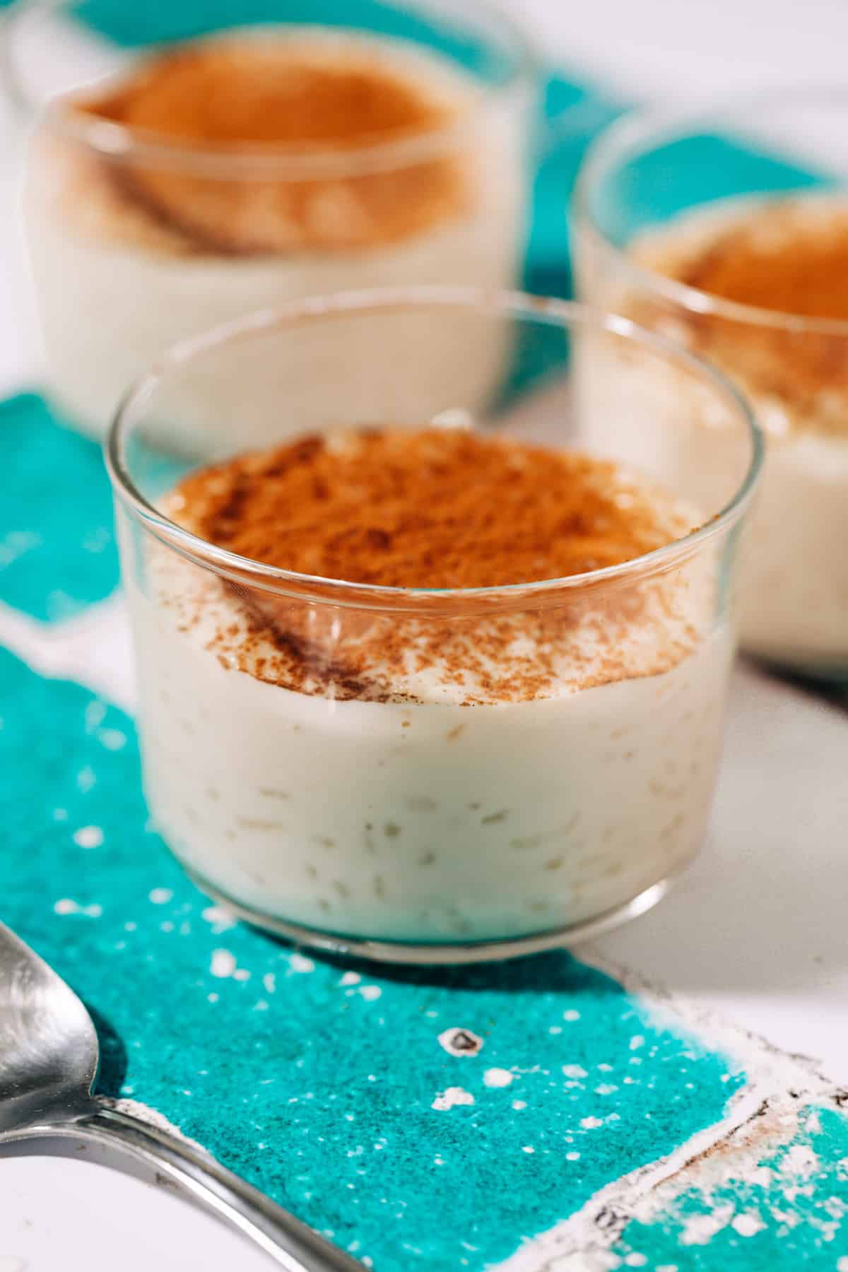 three small bowls of rizogalo topped with cinnamon.