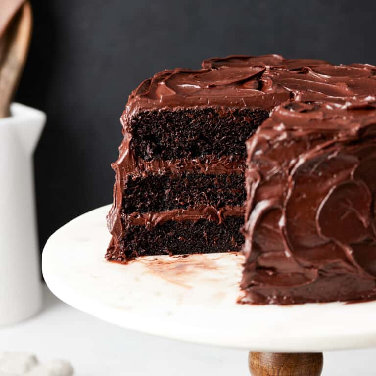 moist chocolate cake with fudge frosting on a cake stand.
