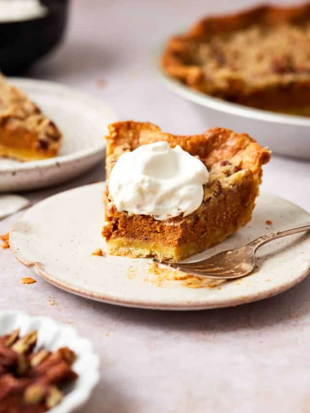 Slice of streusel pumpkin pie topped with whipped cream on a plate.