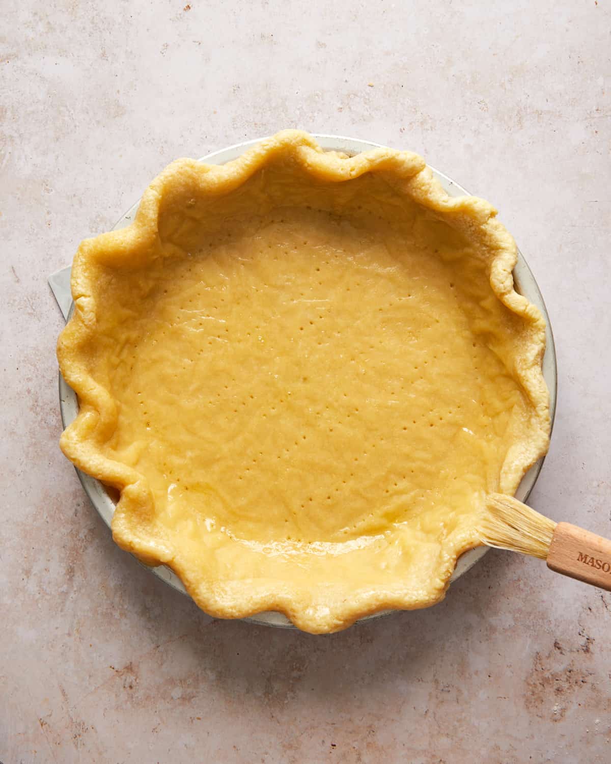 pie crust being brushed with an egg wash.