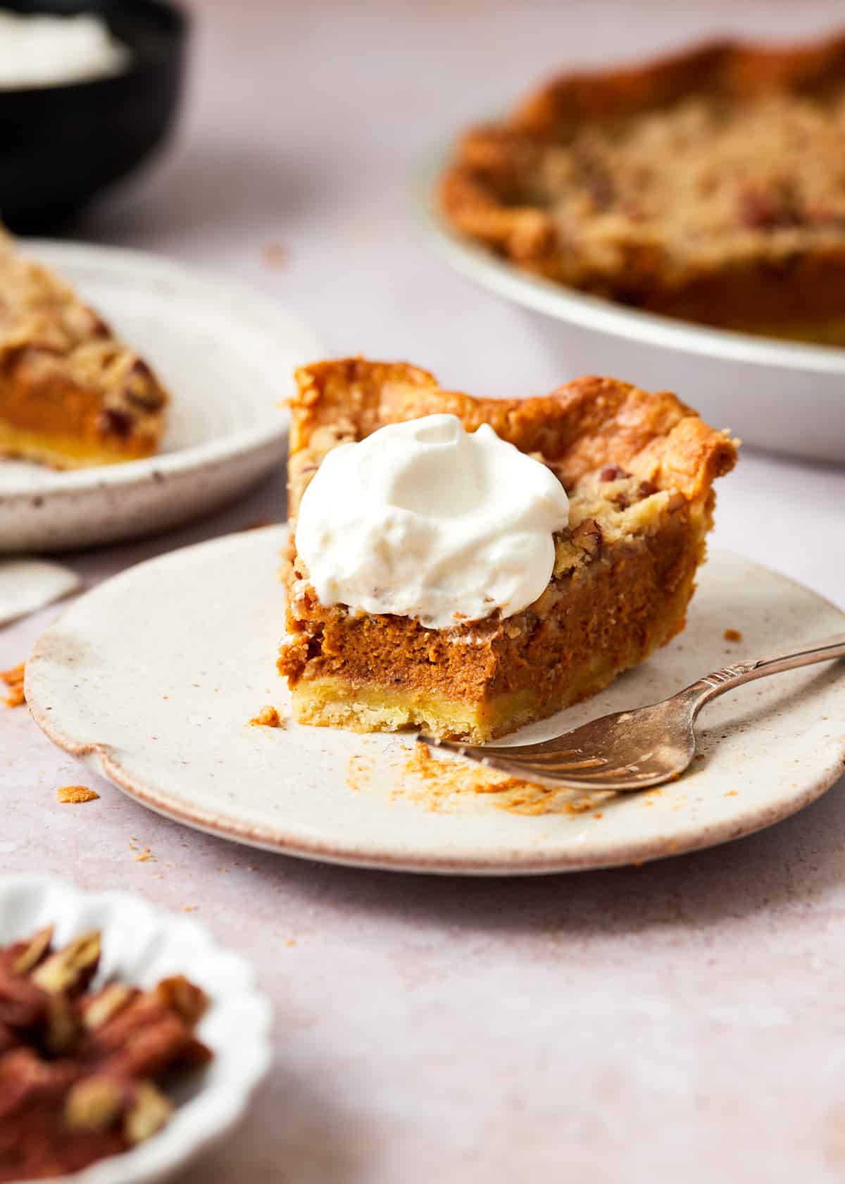 Slice of streusel pumpkin pie topped with whipped cream on a plate.