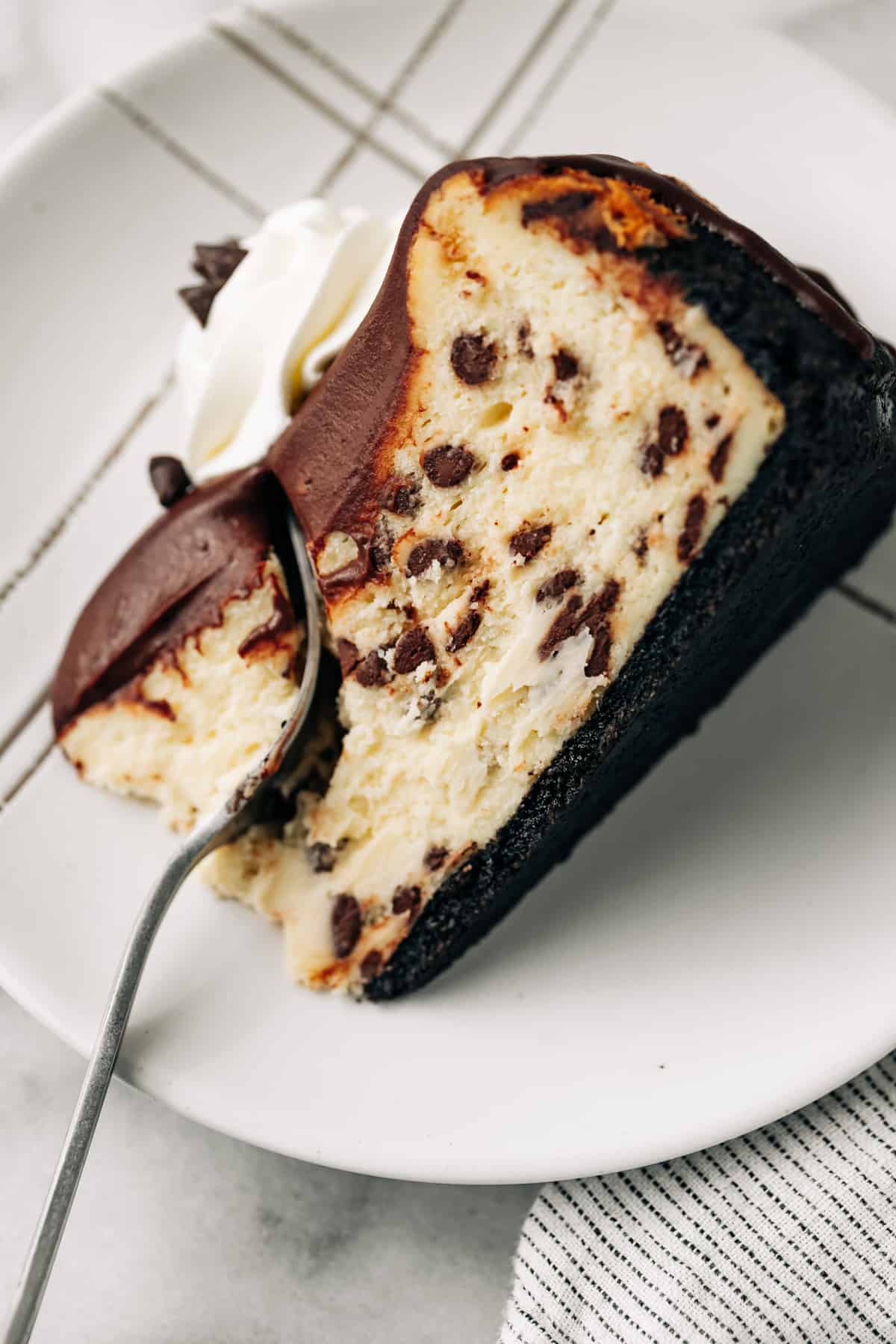 slice of chocolate chip cheesecake with ganache on a plate.